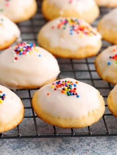 there are many donuts with white frosting and sprinkles on the cooling rack