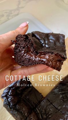 a hand holding a piece of chocolate cheese brownie