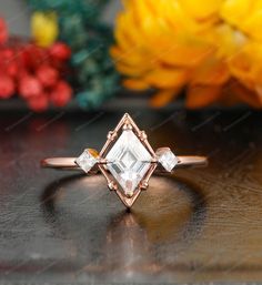 an engagement ring with three diamonds on it and flowers in the backgrouf