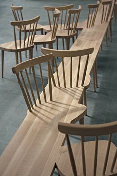 several wooden chairs are lined up in a row on the floor, and one is empty