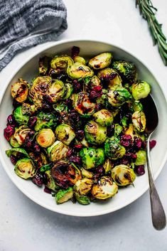 a white bowl filled with brussel sprouts and cranberries