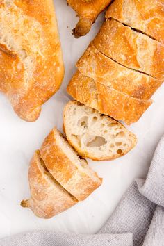 several pieces of bread sitting on top of a piece of parchment paper next to a loaf of bread