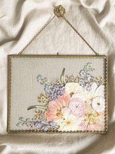 a painting hanging on a wall with flowers in the middle and gold chain around it