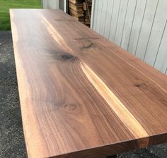 a wooden table sitting in front of a garage door on top of gravel covered ground