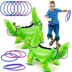 a young boy is playing with an inflatable toy alligator and other rubber rings