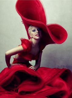 a woman in a red dress and big hat