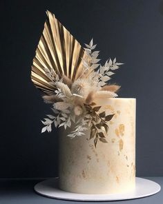 a white cake with gold leaf decoration on top