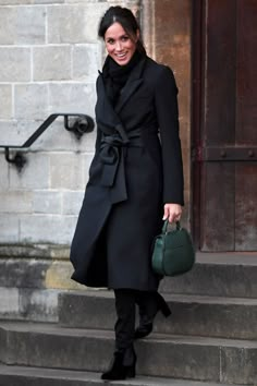 a woman in black coat carrying a green purse