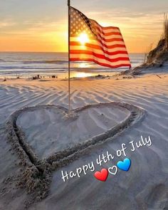 a heart shaped flag on the beach with an inscription happy 4th of july in the sand