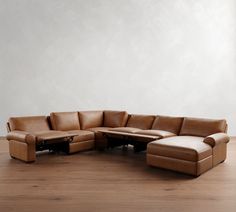 a brown leather sectional sofa sitting on top of a wooden floor next to a white wall