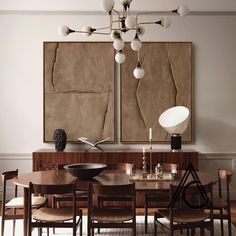 a dining room table and chairs in front of two paintings