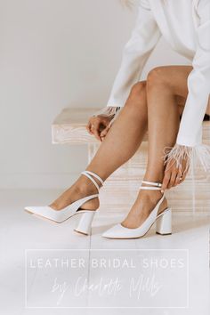 a woman sitting on a bench wearing white shoes with feather trimming around the ankles