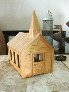 a small wooden house sitting on top of a table next to a metal canister