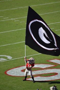 a football player holding a black and white flag on top of a field with other players