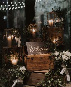 candles are lit in front of wooden boxes with welcome signs and greenery on them