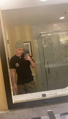 a man taking a selfie in front of a bathroom mirror with his cell phone