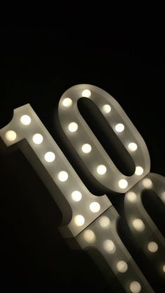 an illuminated sign with the number 90 on it's side in front of a black background