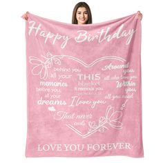 a woman holding up a pink blanket with words on it that says, happy birthday