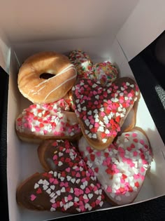 a box filled with lots of donuts covered in sprinkles and frosting