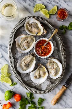 oysters on an ice tray with salsa and lime wedges next to the plate