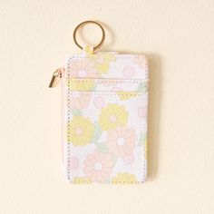 a keychain hanging from the side of a flowered card case on a wall