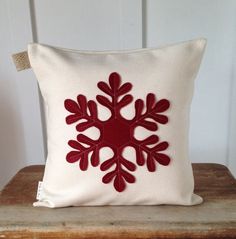 a red and white snowflake pillow sitting on top of a wooden table