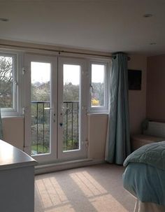 a bed room with a neatly made bed next to a sliding glass door and windows