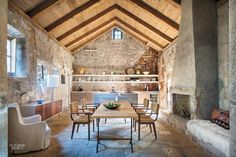 an open living room with stone walls and vaulted ceiling, along with wooden tables and chairs