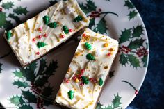 two pieces of cake sitting on top of a white and green plate with holly decorations