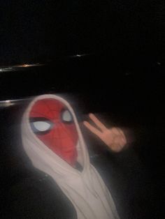 a person wearing a spider man mask with their fingers up