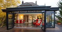 an outdoor living area with red chairs and a gazebo in the middle of it