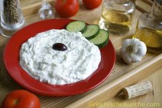 a red plate topped with cucumbers, tomatoes and olives next to other ingredients