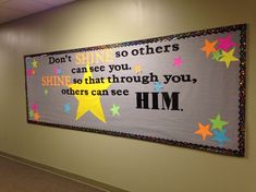 a bulletin board hanging on the wall in an office hallway with colorful stars and words