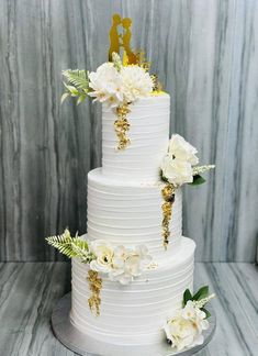 a white wedding cake with gold decorations and flowers