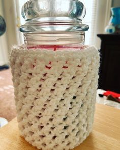 a crocheted jar cover sitting on top of a wooden table