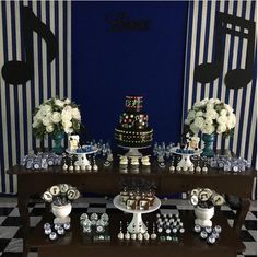 a black and white checkered table topped with cake, cupcakes and flowers