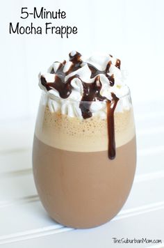 a glass filled with chocolate and marshmallows on top of a white table