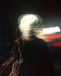 blurry photograph of a person in the dark with their head turned to the side