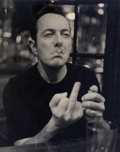 a black and white photo of a man sitting at a table with his fingers in the air