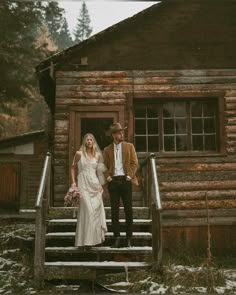 a bride and groom standing on the steps of a cabin