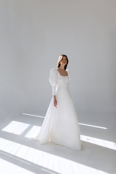 a woman in a white wedding dress posing for the camera with her hands on her hips