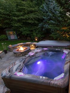 a hot tub sitting next to a fire pit in the middle of a backyard area