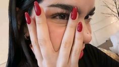 a woman with red nails covering her face