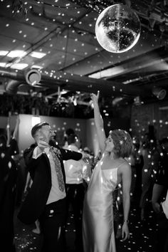 a man and woman dancing at a party with confetti falling from the ceiling