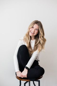 a woman sitting on top of a stool smiling