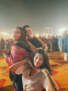 three women are posing for the camera in front of a crowd