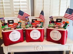 three red coolers with american flags and baseball balls in them on a white table