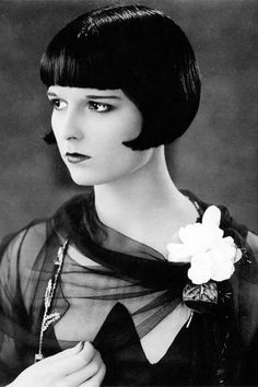 an old photo of a woman with short hair and a flower in her lapel