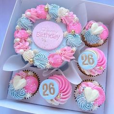 cupcakes in a box decorated with pink, blue and white frosted decorations