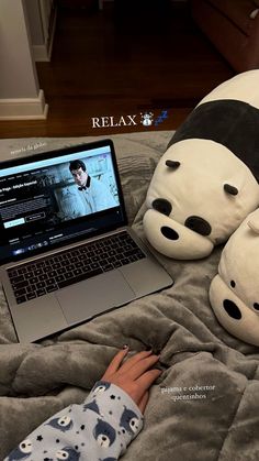 a person laying in bed with a laptop and stuffed animals on top of the bed